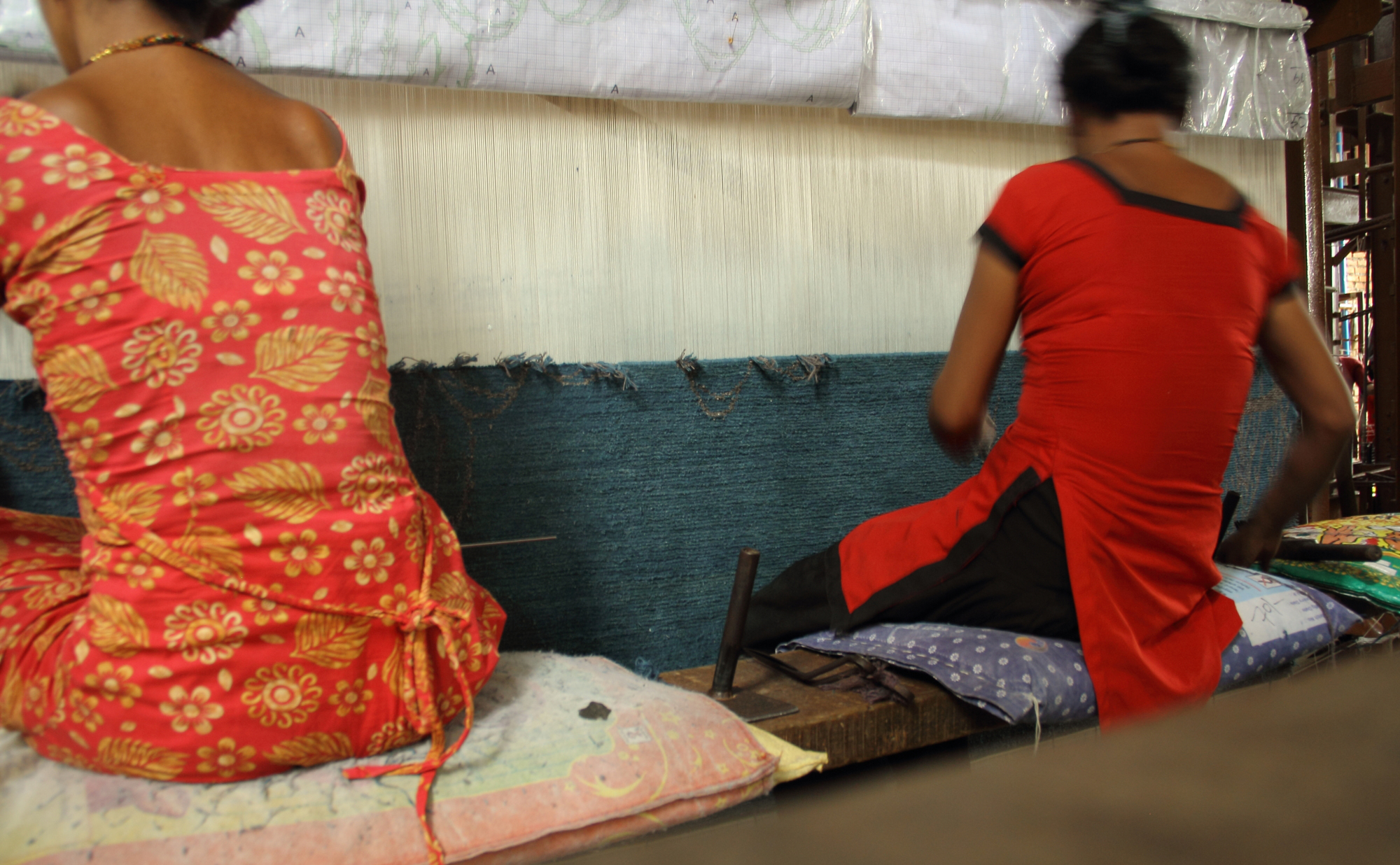 'Asian Quilt' by Kooches is shown on-loom in Kathmandu being woven by two (2) Nepali women. Note the cartoon (design plate) on the loom (at the top of the image) which has the carpet design w/colour references drawn out allowing the weavers to accurately translate the design from concept to reality. | Image courtesy of Kooches.
