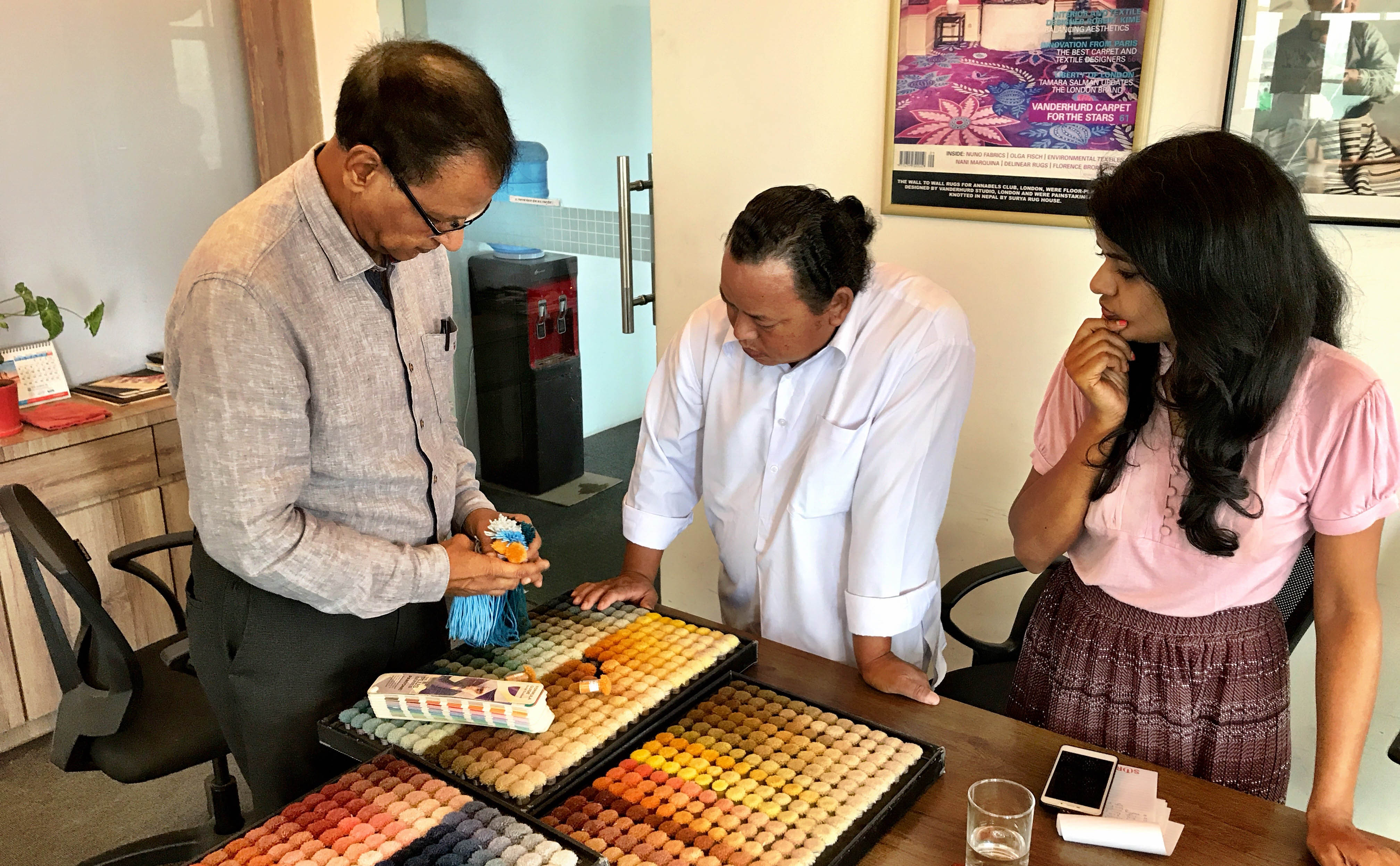 Dev Anand Sarawagi (left) and Shally Sarawagi (right) consult with staff from Sarawagi Rugs' on 17 July 2019 in Kathmandu, Nepal as final colour selections are made for the prototype handknotted rug made from ECONYL® regenerated nylon. | Photograph by The Ruggist.